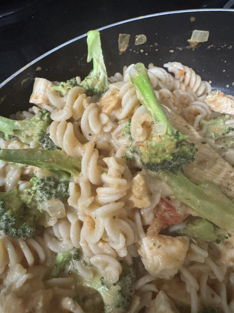 This image is a spoonful of the gluten free creamy rotini pasta. It is a close up pf Rotini noodle, chicken and broccoli.